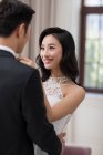 Jovem esposa chinesa ajustando laço para o marido — Fotografia de Stock