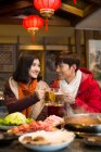 Young Chinese couple drinking beer in hotpot restaurant — Stock Photo