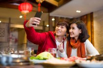 Jeune couple chinois prenant autoportrait avec un téléphone intelligent — Photo de stock