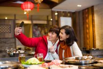 Joven pareja china tomando autorretrato con un teléfono inteligente - foto de stock