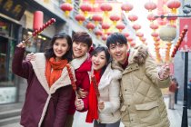 Молодые китайские друзья с засахаренными ягодами мясорубки празднуют китайский Новый год — стоковое фото