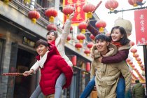 Jóvenes amigos chinos con bayas de haw confitadas celebrando el Año Nuevo Chino - foto de stock