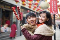 Jovem casal chinês com bagas de haw cristalizadas celebrando o Ano Novo Chinês — Fotografia de Stock