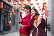 Jovem casal chinês tomando auto retrato com um telefone inteligente — Fotografia de Stock