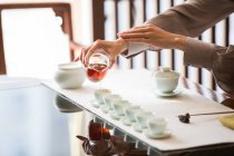 Abgeschnittene Aufnahme einer Frau, die Teezeremonie durchführt und Tee einschenkt — Stockfoto