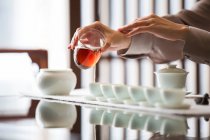 Обрізаний знімок жінки, що виконує чайну церемонію, поливає чай — стокове фото