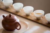 Chinese tea pot and tea cups in row — Stock Photo