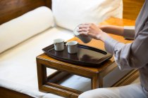 Обрезанный снимок женщины, наливающей чай в чашки из керамического горшка — стоковое фото