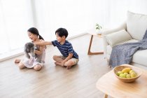 Счастливый китаец играет с собакой в гостиной — стоковое фото