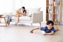 Glückliche chinesische Geschwister spielen mit Spielzeug im Wohnzimmer — Stockfoto