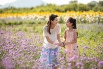 Madre e hija chinas en el campo de flores - foto de stock