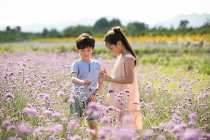 Two Chinese children picking flowers in field — Stock Photo