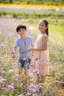 Duas crianças chinesas colhendo flores no campo — Fotografia de Stock
