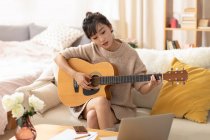 Mujer aprendiendo a tocar la guitarra en casa - foto de stock