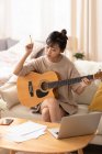 Жінка вчиться грати на гітарі вдома — стокове фото