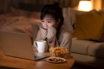 Молода китайка дивиться фільм на ноутбуці. — стокове фото