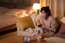 Jovem chinesa jogando videogame no sofá — Fotografia de Stock
