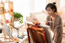 Young Chinese woman painting at home — Stock Photo