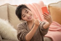 Joven mujer china haciendo webcast en vivo en casa - foto de stock