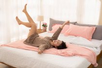 Junge Chinesin entspannt sich auf Bett — Stockfoto