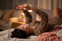 Молода китайська жінка використовує смартфон у ліжку — стокове фото