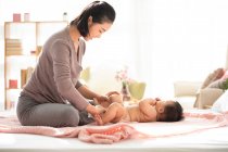 Jovem mãe chinesa mudando fralda do bebê — Fotografia de Stock