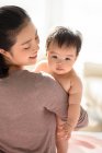 Young chinese mom holding her baby — Stock Photo