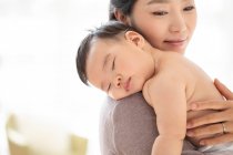 Young chinese mom holding her sleeping baby — Stock Photo
