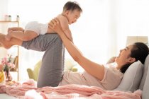 Mother and baby playing and laughing on couch — Stock Photo