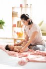 Young chinese mom smiling and playing with baby on couch — Stock Photo