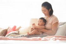 Mamma tenendo il bambino mentre seduto sul divano — Foto stock