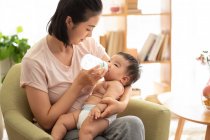 Junge Mutter füttert ihr Baby aus Babyflasche — Stockfoto