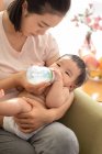 Jovem mãe alimentando seu bebê de mamadeira — Fotografia de Stock