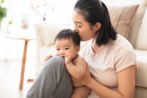 Portrait of young mother kissing her baby — Stock Photo