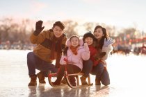 Feliz jovem chinês família trenó ao ar livre — Fotografia de Stock