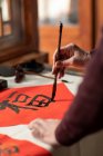 Cropped shot of senior man hands writing calligraphy on couplets — Stock Photo