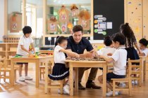 Іноземний вчитель і діти грають у класі — стокове фото