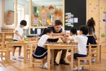 Professora estrangeira e crianças brincando em sala de aula — Fotografia de Stock
