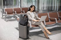 Mulher usando laptop enquanto sentado no aeroporto — Fotografia de Stock