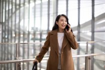 Жінка з багажем розмовляє по телефону в аеропорту — стокове фото