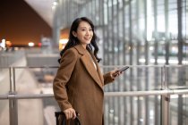Donna con smartphone e bagagli in aeroporto — Foto stock