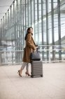 Young woman walking with luggage in airport — Stock Photo