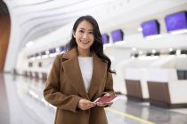 Happy woman with passport and airplane ticket in airport — Stock Photo