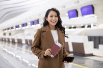 Donna felice con passaporto e biglietto aereo in aeroporto — Foto stock