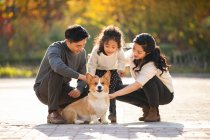 Happy young Chinese family and pet dog in park — Stock Photo