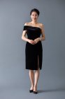 Beautiful mature chinese woman posing in black dress on gray studio background — Stock Photo
