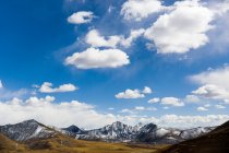 Живописный вид на долину и скалистые горы под голубым облачным небом в Тибете, Китай — стоковое фото