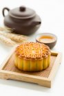 Mooncake and tea in cup and teapot with spikelets on white table — Stock Photo