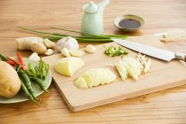 Pommes de terre hachées et autres ingrédients avec couteau sur planche à découper — Photo de stock