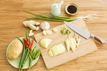 Batata picada e outros ingredientes com faca na tábua de corte — Fotografia de Stock